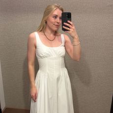 Woman wears white basque waist dress by Abercrombie