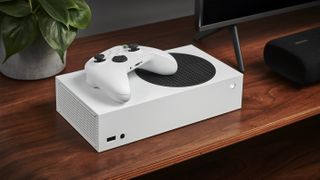 An Xbox Series X in white, with a white controller on top, both set out on a wooden TV stand next to a television.