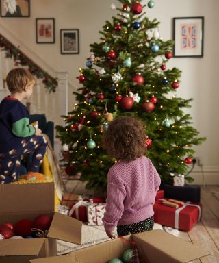 Christmas tree in living room being decorated by children