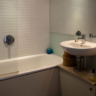 bathroom with white wall tiles and wash basin with bathtub