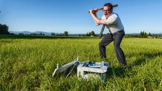 A businessman or IT professional beats on a laser printer in a field