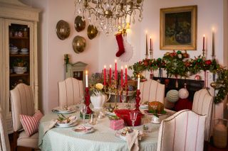 Christmas table setting with gingham tablecloth, gold candelabra, red candlesticks, garland on mantle