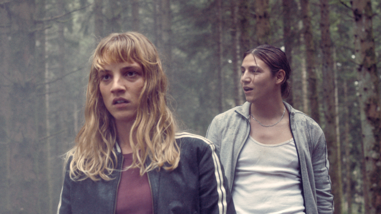 An angry-looking Megan Northam guides a man through the woods in Meanwhile on Earth.