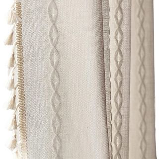 A white curtain with a plaited pattern and tassel trim