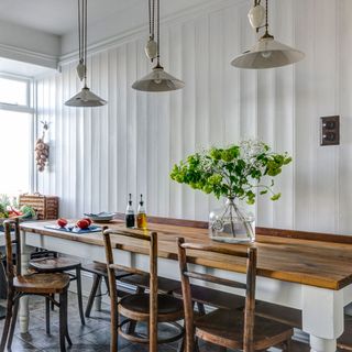 white dining room with wooden wall panelling and a long dining table