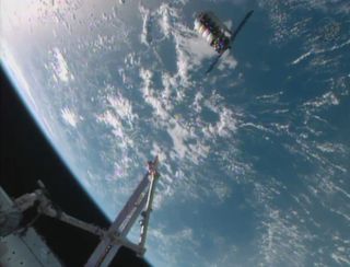 Orbital Sciences' first Cygnus spacecraft to visit the International Space Station hovers near the station in this still from a NASA TV broadcast during the cargo ship's first rendezvous with the orbiting lab on Sept. 29, 2013.