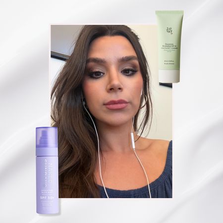two bottles of face sunscreen, one purple and one green, flanking a tan brunette woman wearing cord headphones taking a selfie on a silver background