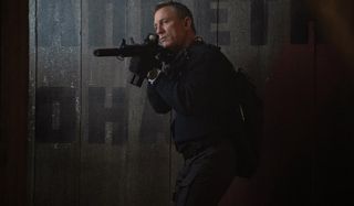 Daniel Craig takes careful aim in a shadowy room in No Time To Die.