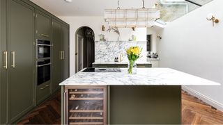 Olive green kitchen with large kitchen island with white marble countertops and skylights