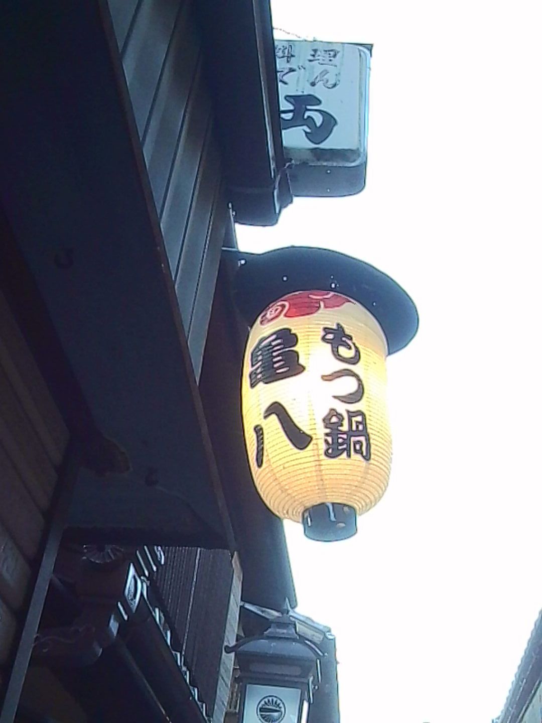 Close-up of a glowing paper lantern hanging outside a Japanese restaurant.