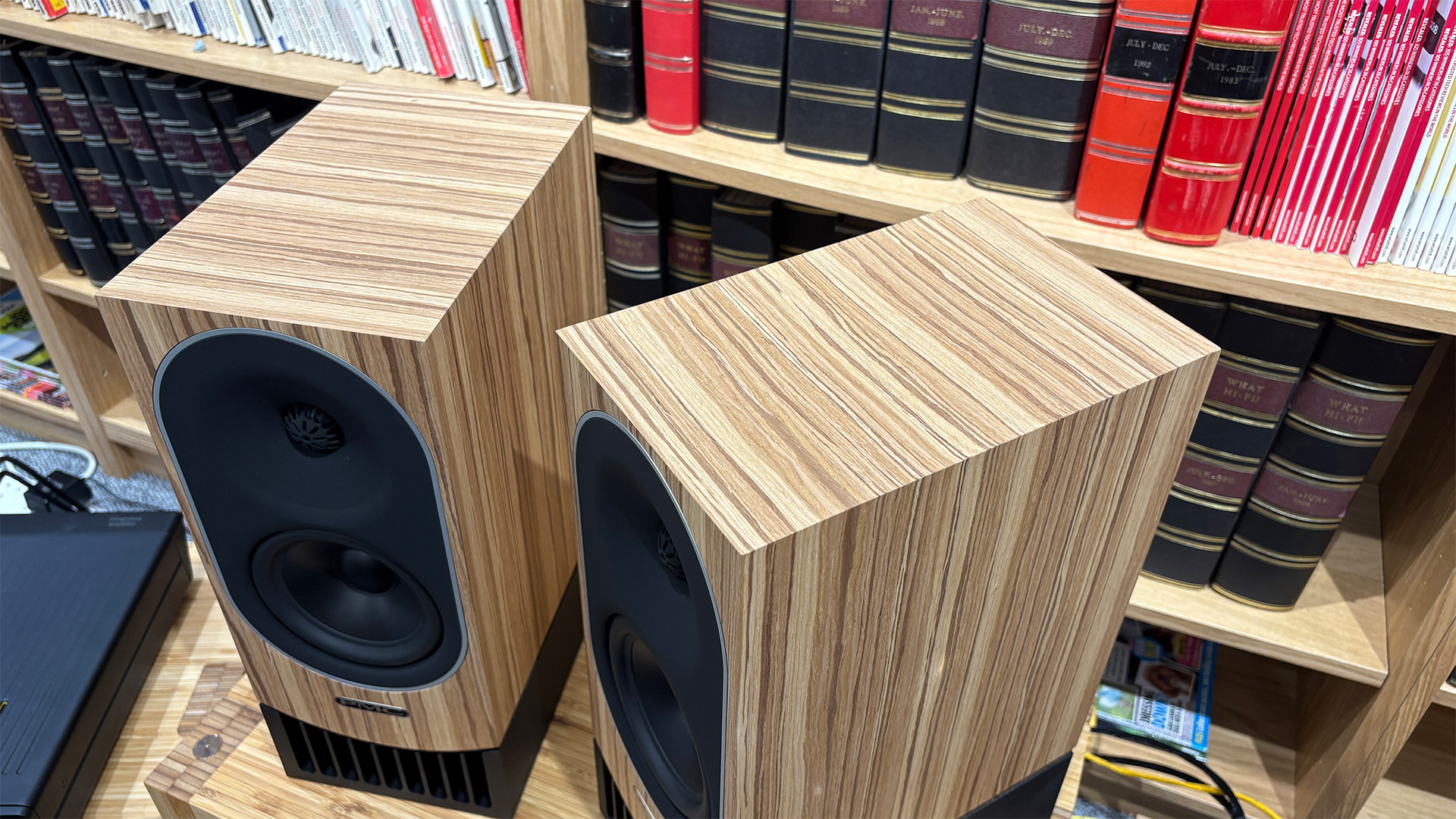 PMC Prophecy 1 standmount speakers in front of bookcase, slight top-down angle