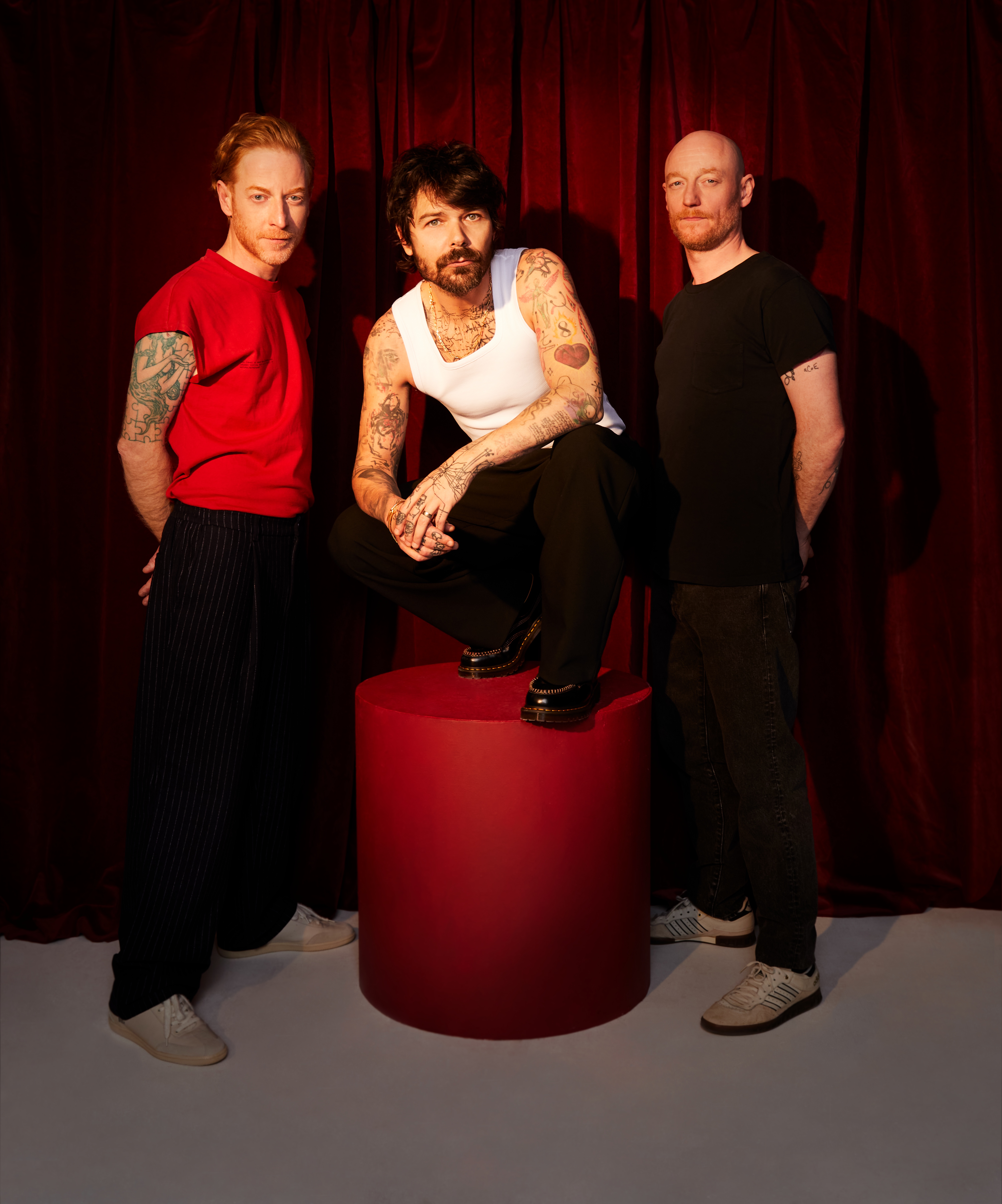 All three Biffy Clyro members posing against a red background