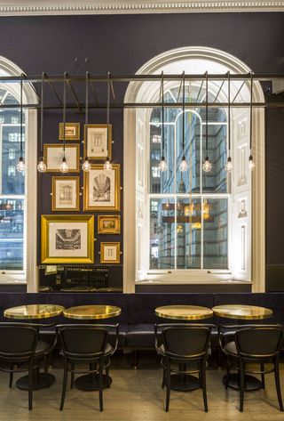 Showcasing of a space that is dotted with antiqued bronzed mirrors, bespoke banquettes, and playful illustrations of 19th century figures
