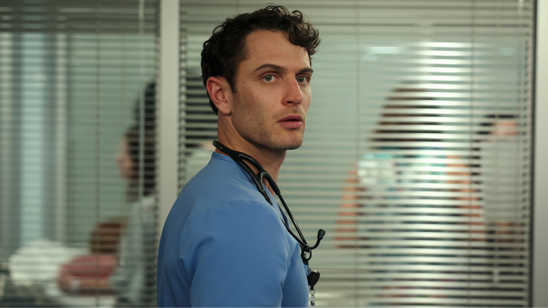 Xander Phillips wears scrubs looking off into the distance