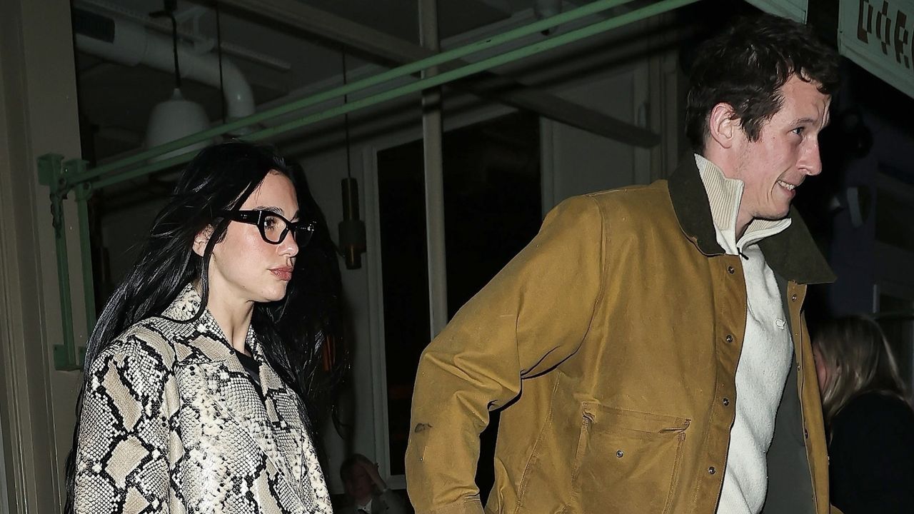 Dua Lipa holds hands with rumored fiance Callum Turner while wearing a snakeskin trench coat and carrying a Chanel 25 handbag