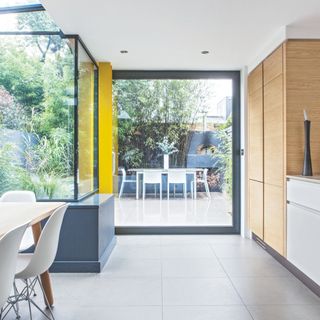 Open plan kitchen diner extension with natural wood and white units and large swatches of glazing to the garden