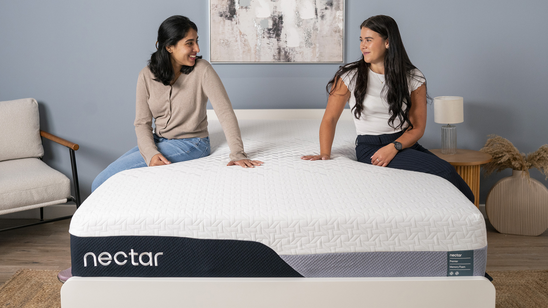 Two mattress testers sitting on the Nectar Premier Memory Foam Mattress in a bedroom, testing the bed to see if it deserves a place in our memory foam mattress guide