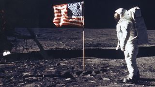 Buzz Aldrin on surface of the moon next to the American flag.