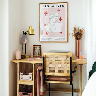 Wooden desk and chair, vase of dried flowers, wall art