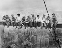Eleven ironworkers sit shoulder to shoulder on a steel I-beam suspended high above the Manhattan skyline, eating lunch and chatting with no safety equipment in sight.