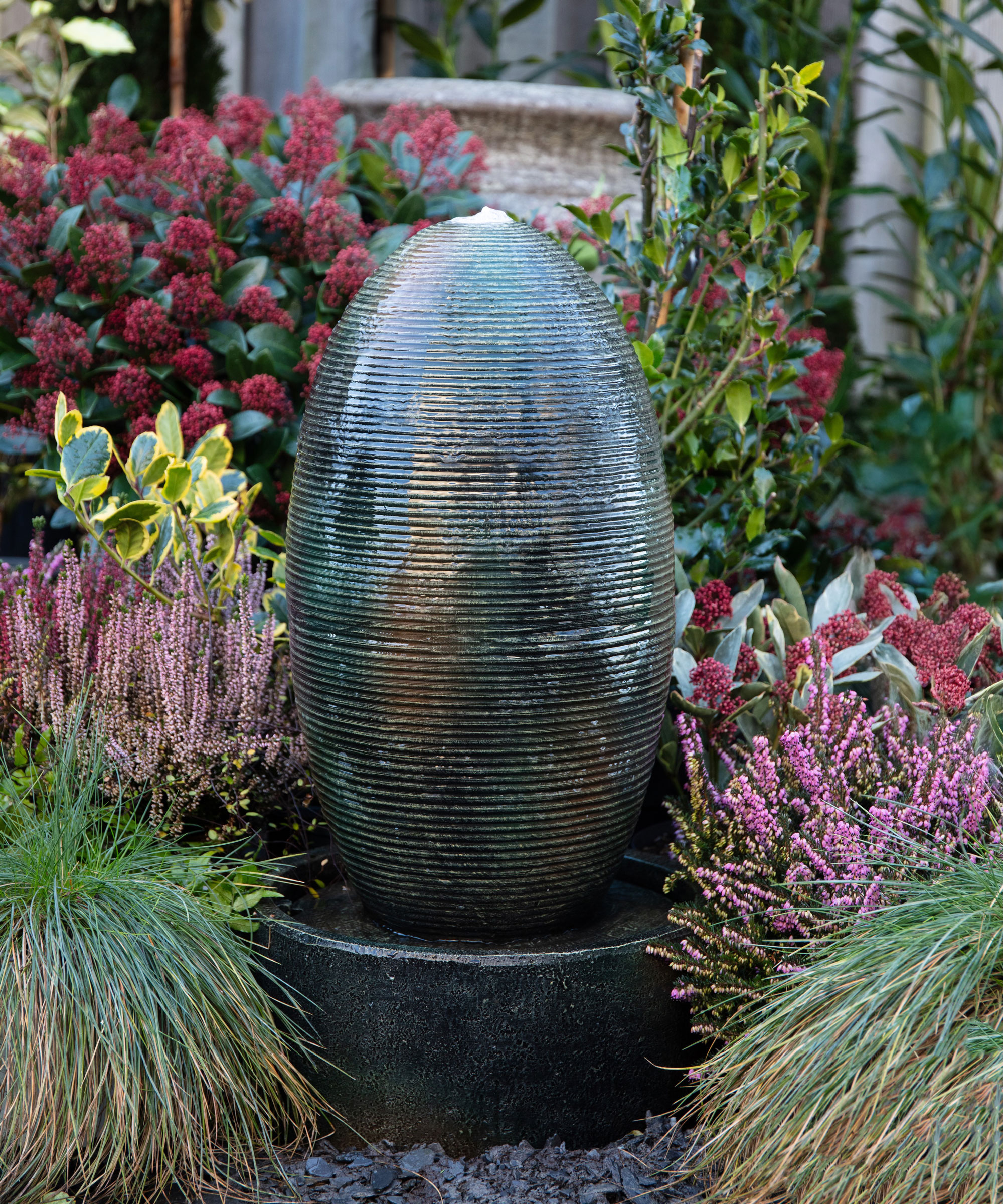 trickle effect water feature surrounded by ornamental grasses and flowering shrubs