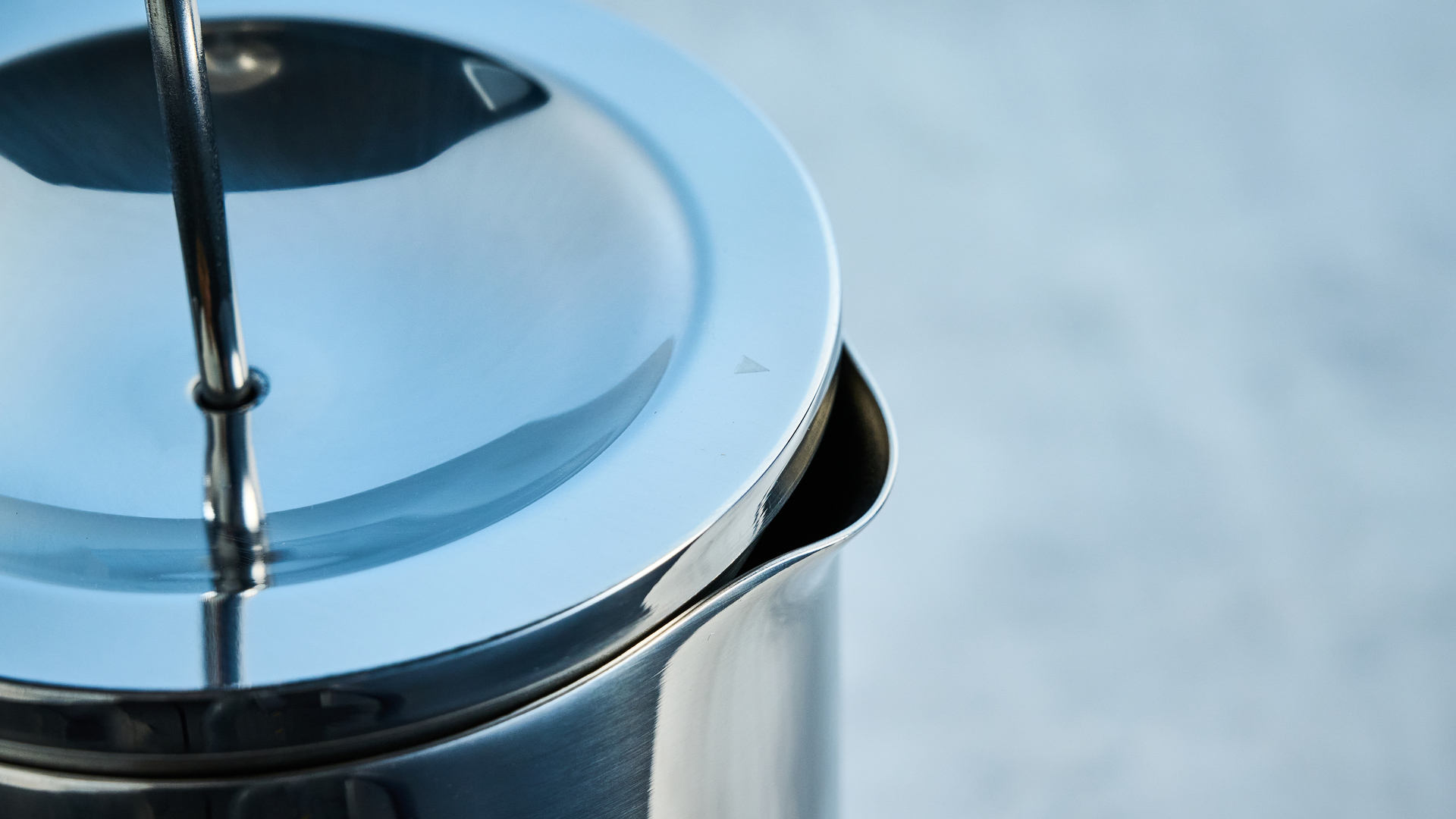 the aarke french press in silver showing the french press filter system, lid, spout, and inside photographed against the blue tom's guide background