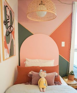 A colorblocked wall with DIY headboard in coordinating colors and framed wall art decor in girls room