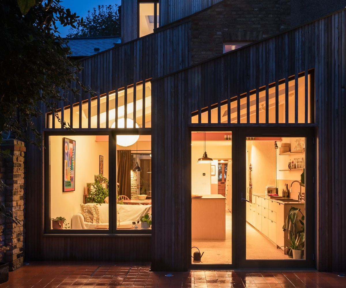 Kitchen extension with double pitched roof extension. It's evening time and the inside lights are lit creating a warm ambient glow