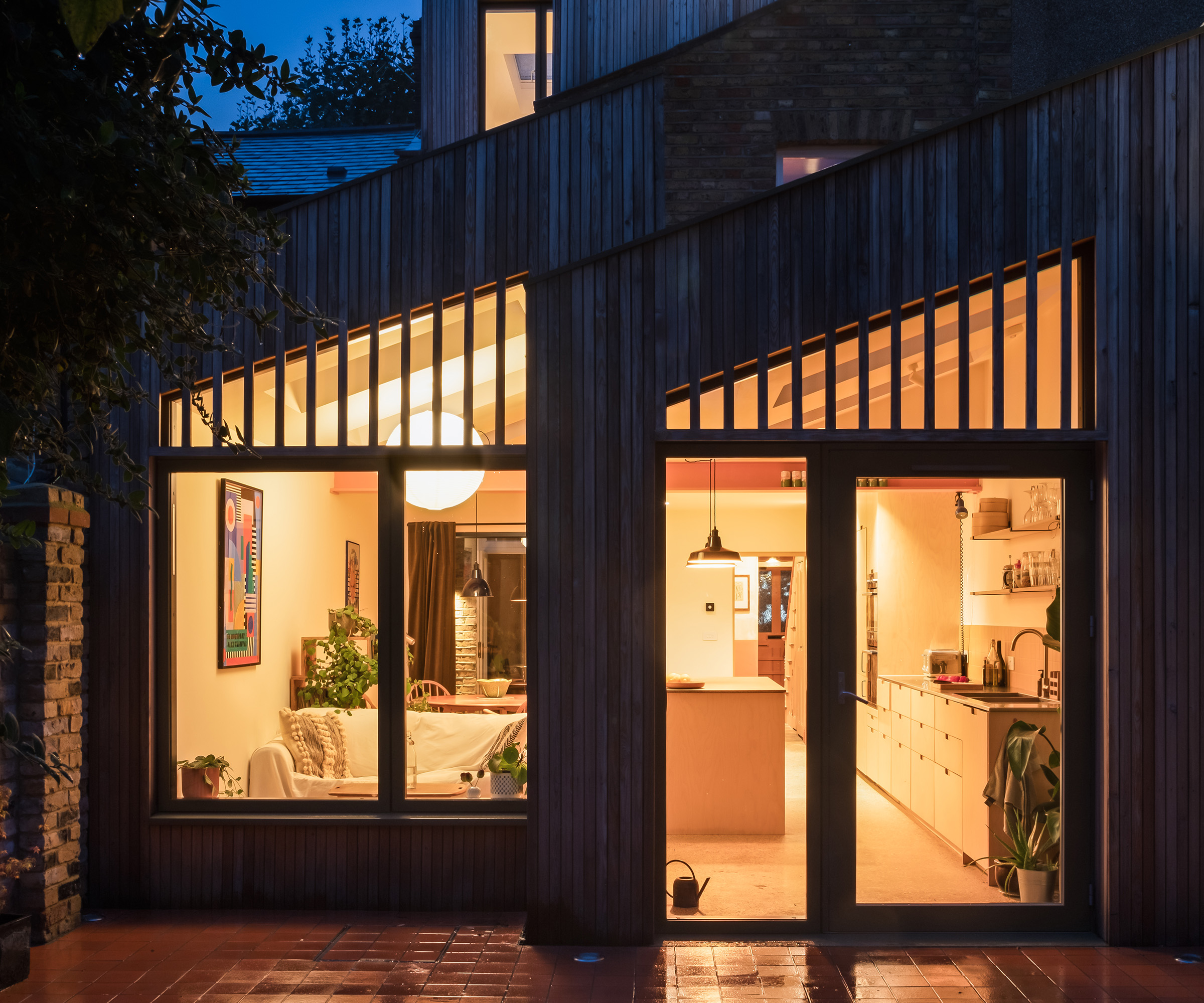 Kitchen extension with double pitched roof extension. It's evening time and the inside lights are lit creating a warm ambient glow