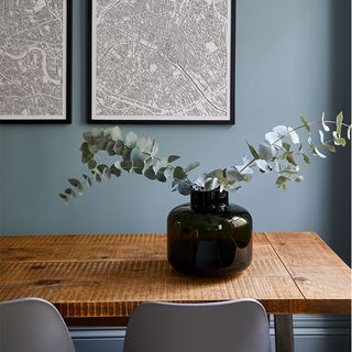 blue dining room with wooden dinning table and grey chairs and frame on wall