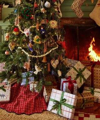 traditional christmas tree by the fire decorating with a mis match of ornaments with a ruffled printed tree skirt