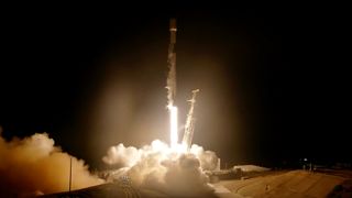 a black and white rocket launches into a dark night sky