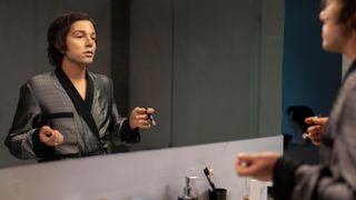 Andy (Diego Luna) in a smoking jacket looking in the mirror in Hulu's "La Maquina"