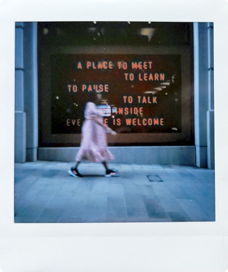 Digitized instant photo taken with the Fujifilm Instax SQ40 of a London bar with person in motion blur walking past