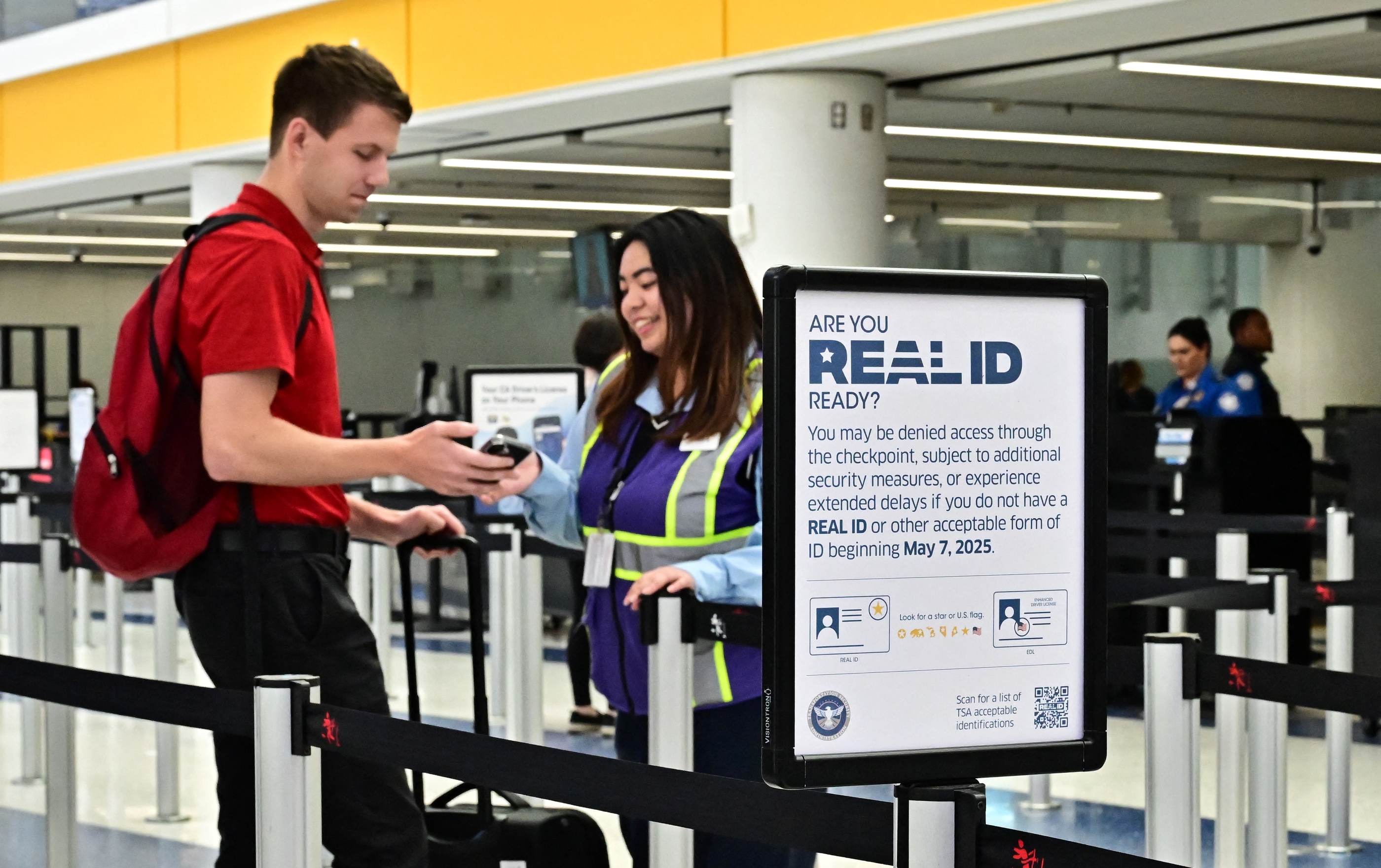 A passenger shows his phone to a TSA agent before going into the security line. 