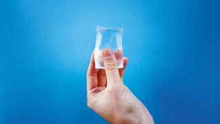 hand holding a transparent package of water