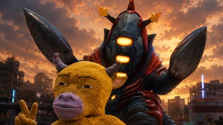 A furry, horned yellow cow character makes a peace sign in front of a towering armoured monster with glowing orange eyes, set against a ruined cityscape at sunset.
