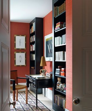 desk with orange walls and bookshelves