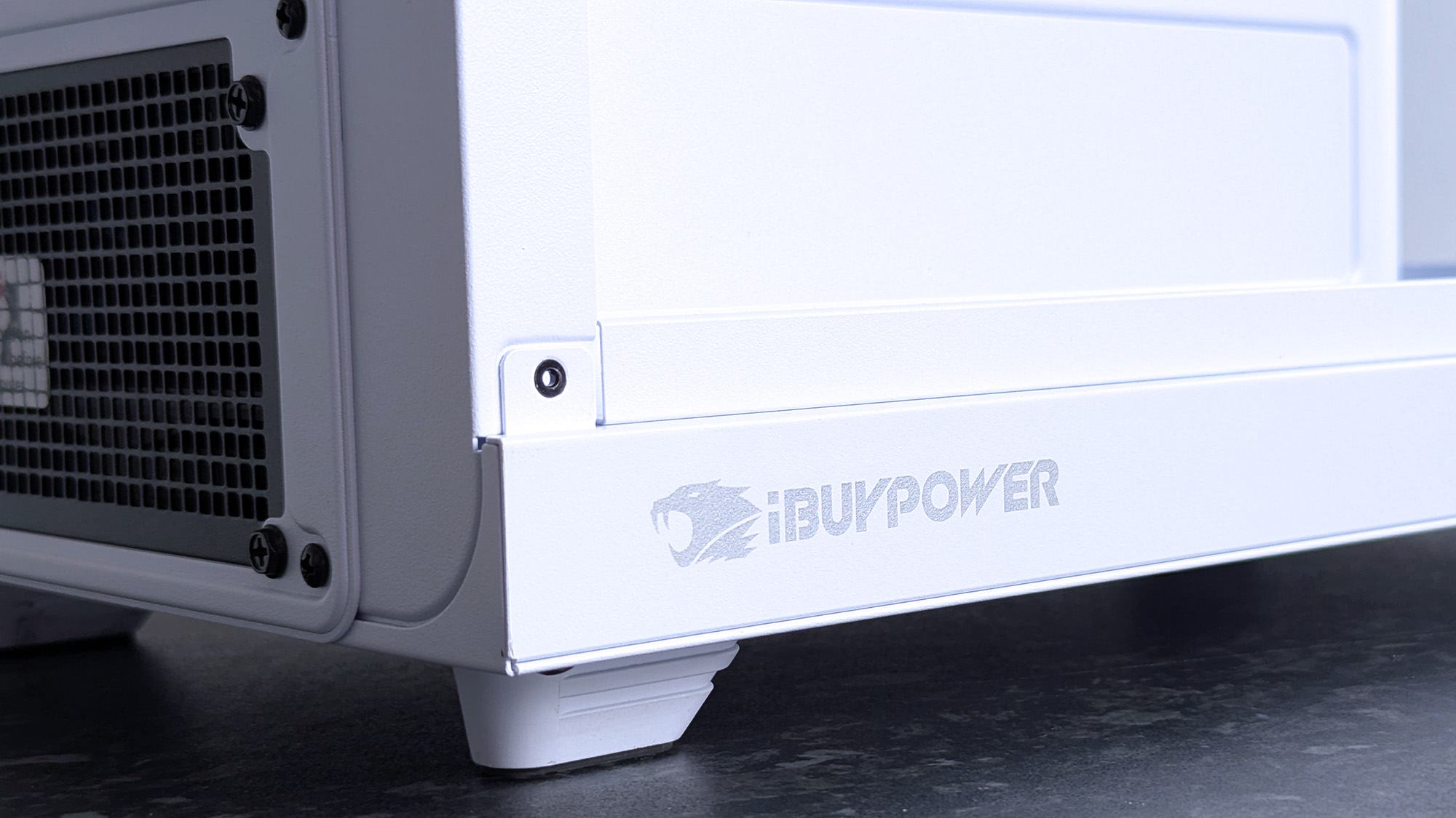 Close-up of a sleek white iBUYPOWER RDY Trace X R01 pre-built gaming PC case with a perforated vent and logo on the lower front panel.
