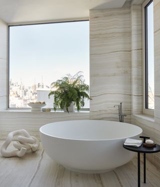 minimalist bathroom with freestanding tub and large window overlooking city skyline