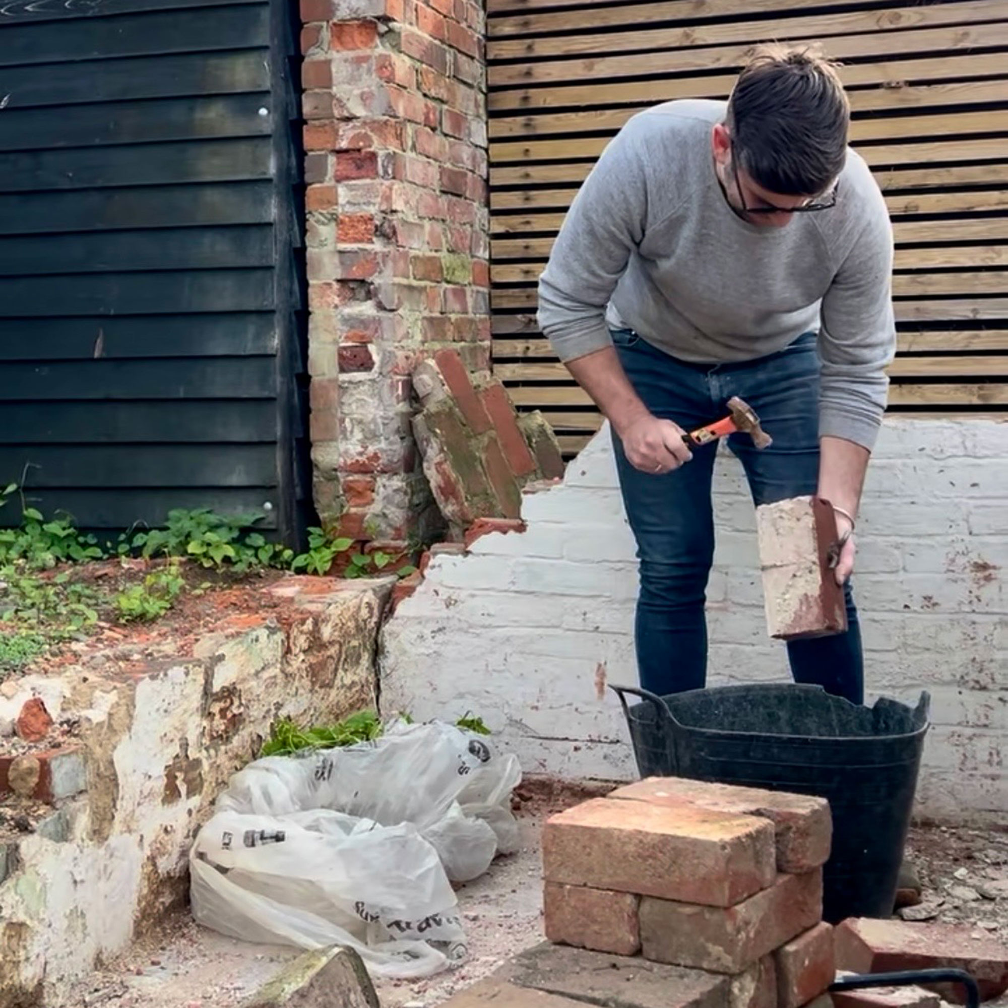 Man holding hammer over brick in garden under renovation and construction