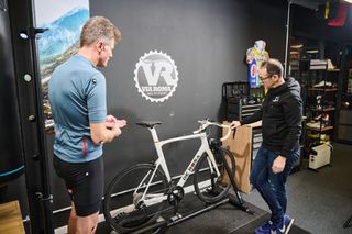 A bike fitter looking at a bike as he begins to diagnose any bike setup issues that could be causing the cyclist to suffer from knee pain while cycling