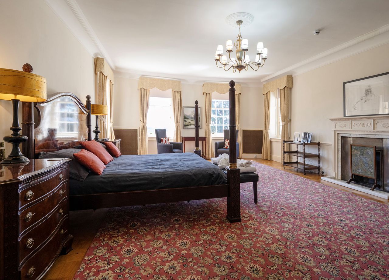 The bedroom has bannisters and a fireplace opposite