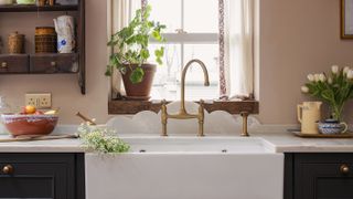 Butler sink with curved marble splashback and brass kitchen tap