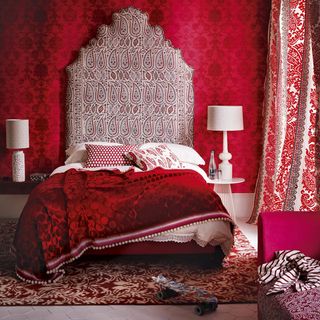 bedroom with red wall and bedding with cushions and throws