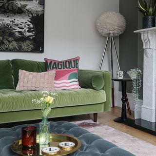 Living room with a green velvet sofa and floor lamp.