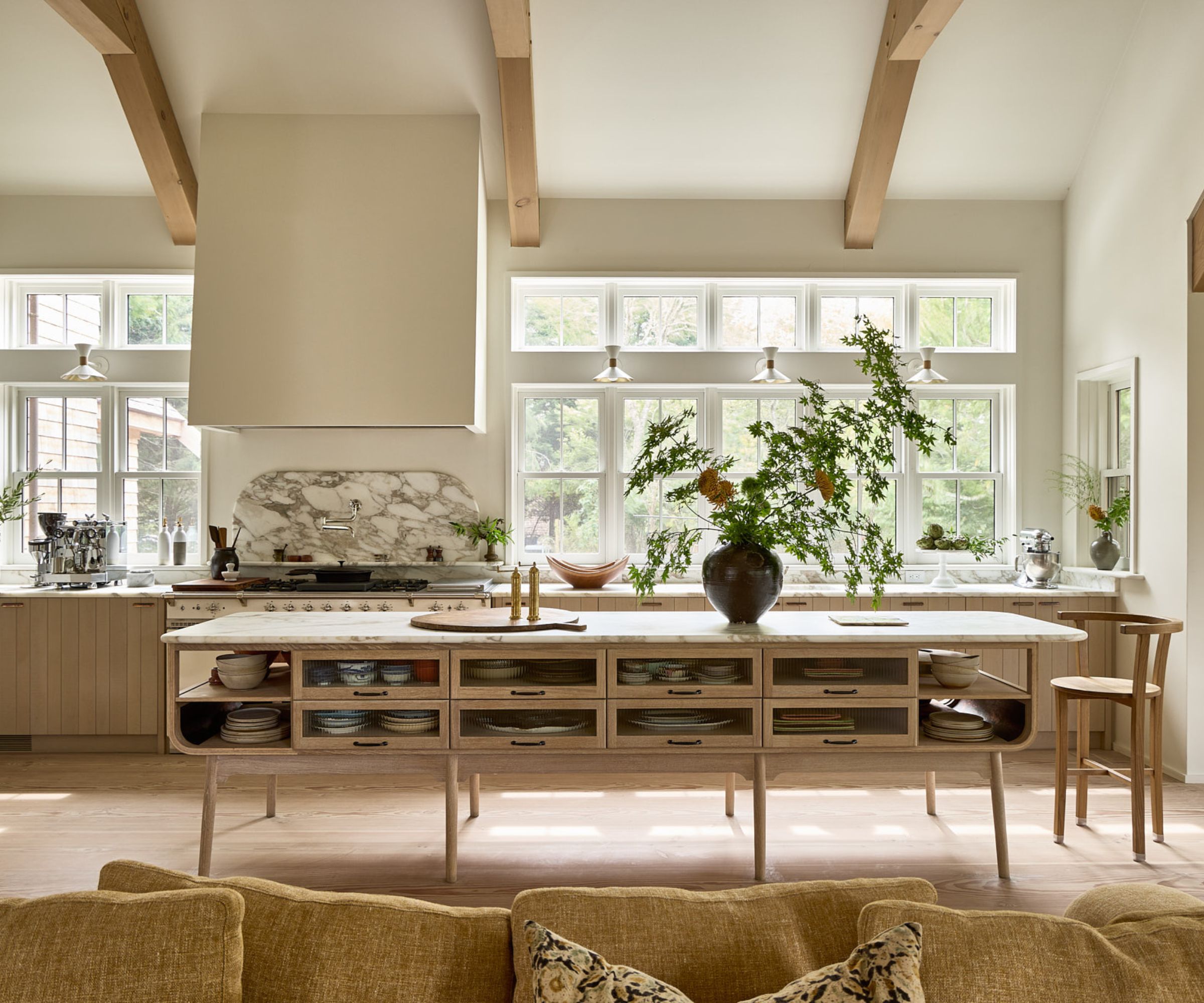 A Coastal Scandinavian kitchen with wooden deVOL cabinets, marble countertops, and a wall of windows