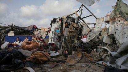Displaced Palestinians inspect their tents destroyed by Israel's bombardment, adjunct to an UNRWA facility west of Rafah city, Gaza Strip