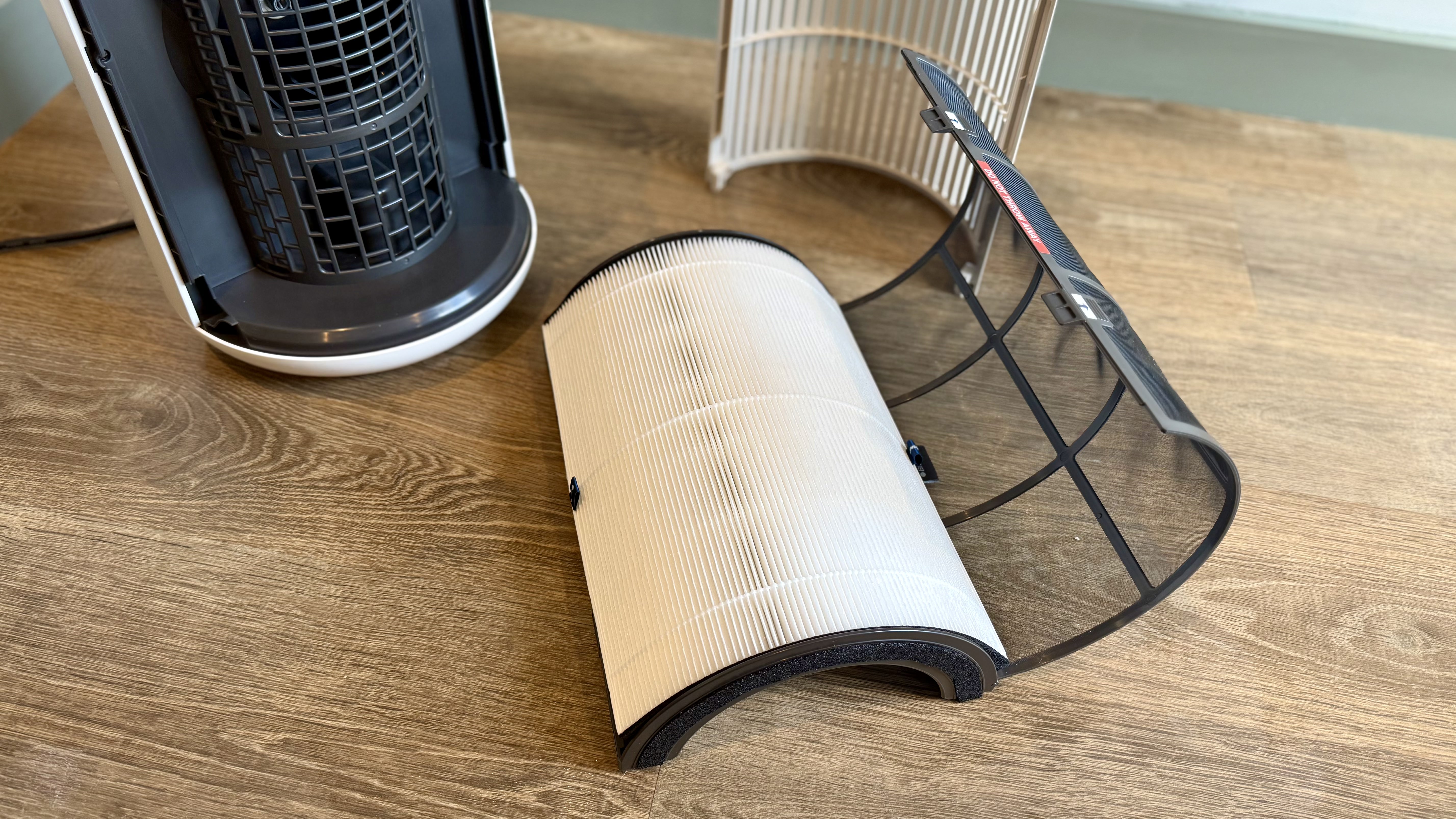 A photo of the Blueair T20i Air Purifier with its remote in a room with white walls and laminated wooden floors