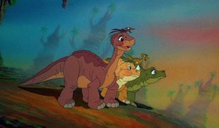 Littlefoot and his dinosaur friends stand smiling on a hill in The Land Before Time.